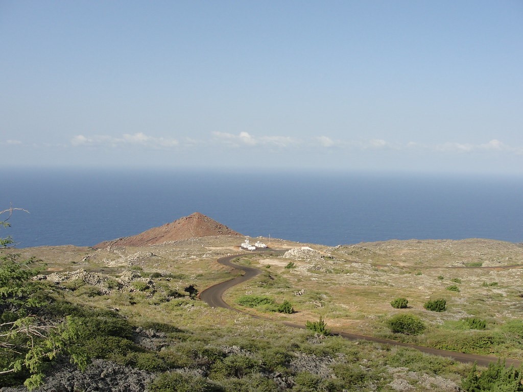 On the coast of Ascension Island, an ARM mobile facility is dwarfed by the vastness of the southeast Atlantic Ocean, rimmed by a line of distant marine low clouds. Such clouds were the target of Paquita Zuidema’s 2016―2017 Layered Atlantic Smoke Interactions with Clouds (LASIC) field campaign. Photo is by Brad Isom, then at Atmospheric Radiation Measurement (ARM) user facility.