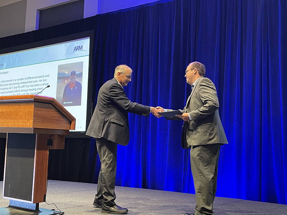 ARM Director Jim Mather shakes hands with 2023 ARM Service Award recipient Max Grover, a software developer from Argonne National Laboratory in Illinois.