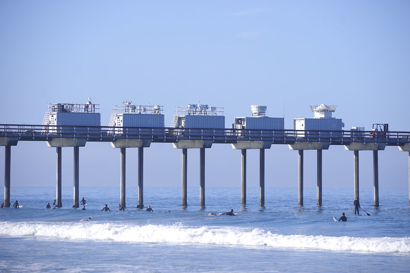 ARM instruments and containers on Scripps Pier are readied for EPCAPE as beachgoers frolic in the water below. 