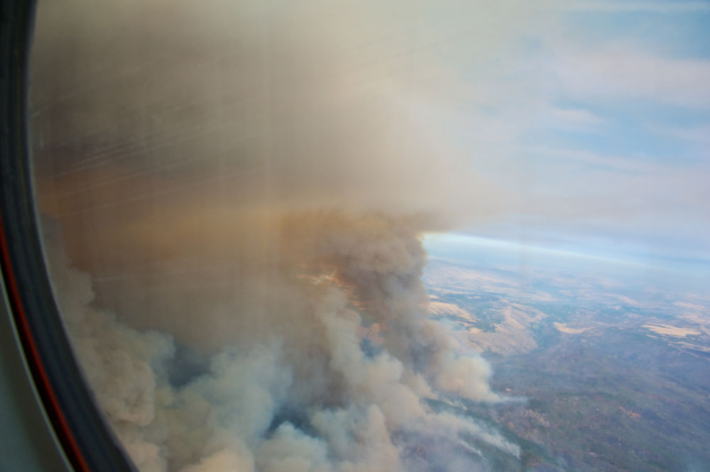 In this view from ARM’s now-retired Gulfstream-159 (G-1) research aircraft, a smoke plume blooms into the sky from the August 2013 Government Flat Complex wildfire in Oregon. The small particles in such smoke evolve as they move downwind, providing insights into how wildfires influence earth system changes. 