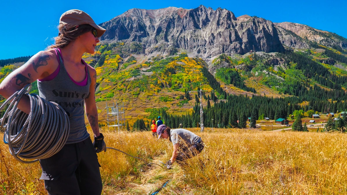 In September 2021, Anna Hodshire of Handix Scientific, left, helps unspool armored ethernet cable for a portable aerosols-measurement unit during the early days of the Surface Atmosphere Integrated Field Laboratory (SAIL) campaign near Gothic, Colorado. With her is Handix’s Kate Patterson, in a gray shirt. Photo by Dean Krakel is courtesy of the Colorado Sun.