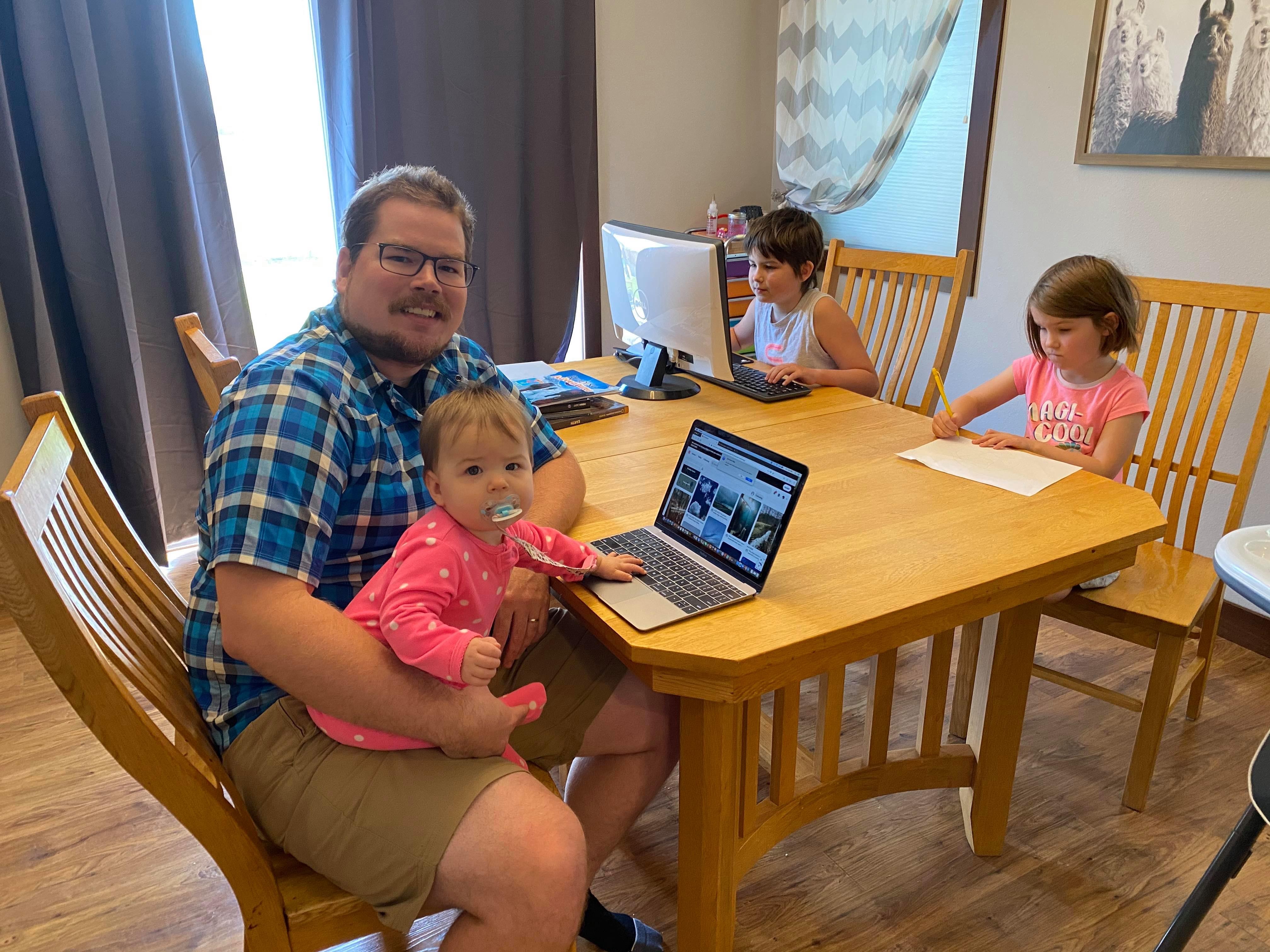 Kennedy at home in Grand Forks, North Dakota, with daughters Juniper (on his lap), Zoey), and Carter (with pencil and paper).