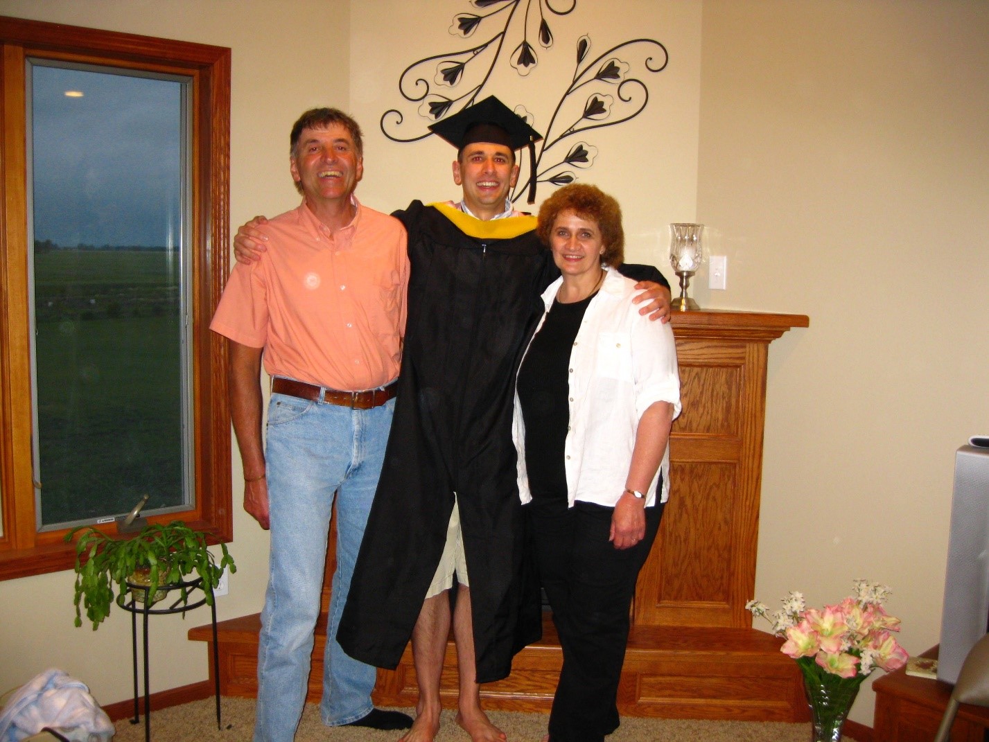 Theisen, center, celebrates with his parents, Robert and Judy, on the day he received his master’s degree from the University of North Dakota.