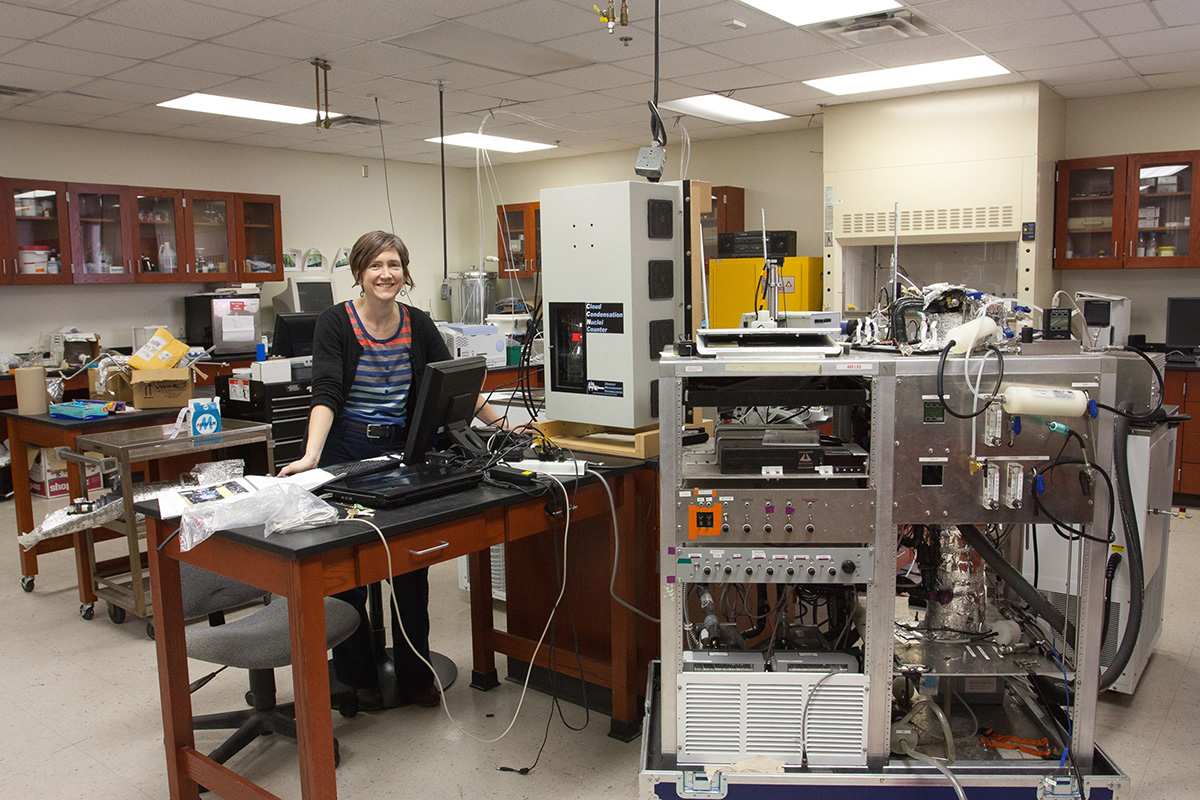 Brooks, surrounded by aerosol instrumentation, poses in her lab at TAMU. Photo is courtesy of Brooks.