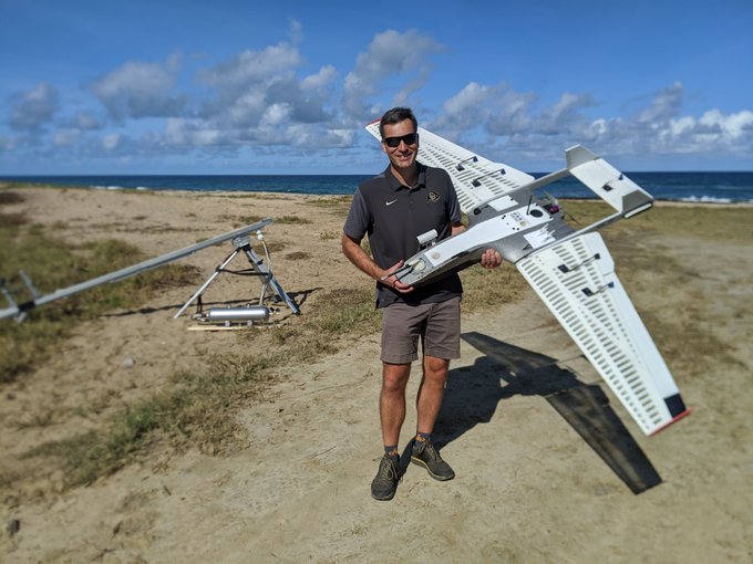 Atmospheric scientist Gijs de Boer poses with a RAAVEN uncrewed aerial vehicle during a 2020 research trip in Barbados to study tropical clouds. Photo courtesy of NOAA.