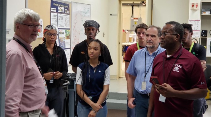 During a 2023 visit to Brookhaven National Laboratory (BNL), Vrinceanu, center right in a blue shirt, and RENEW co-PI Bruce Prince, in the maroon shirt, join TSU interns for an overview of sPHENIX, a radically updated version of the Pioneering High Energy Nuclear Interaction eXperiment (PHENIX). In the pink shirt at left is presenter Ed O’Brien, assistant chair of the BNL Physics Department and former director of the sPHENIX project. 