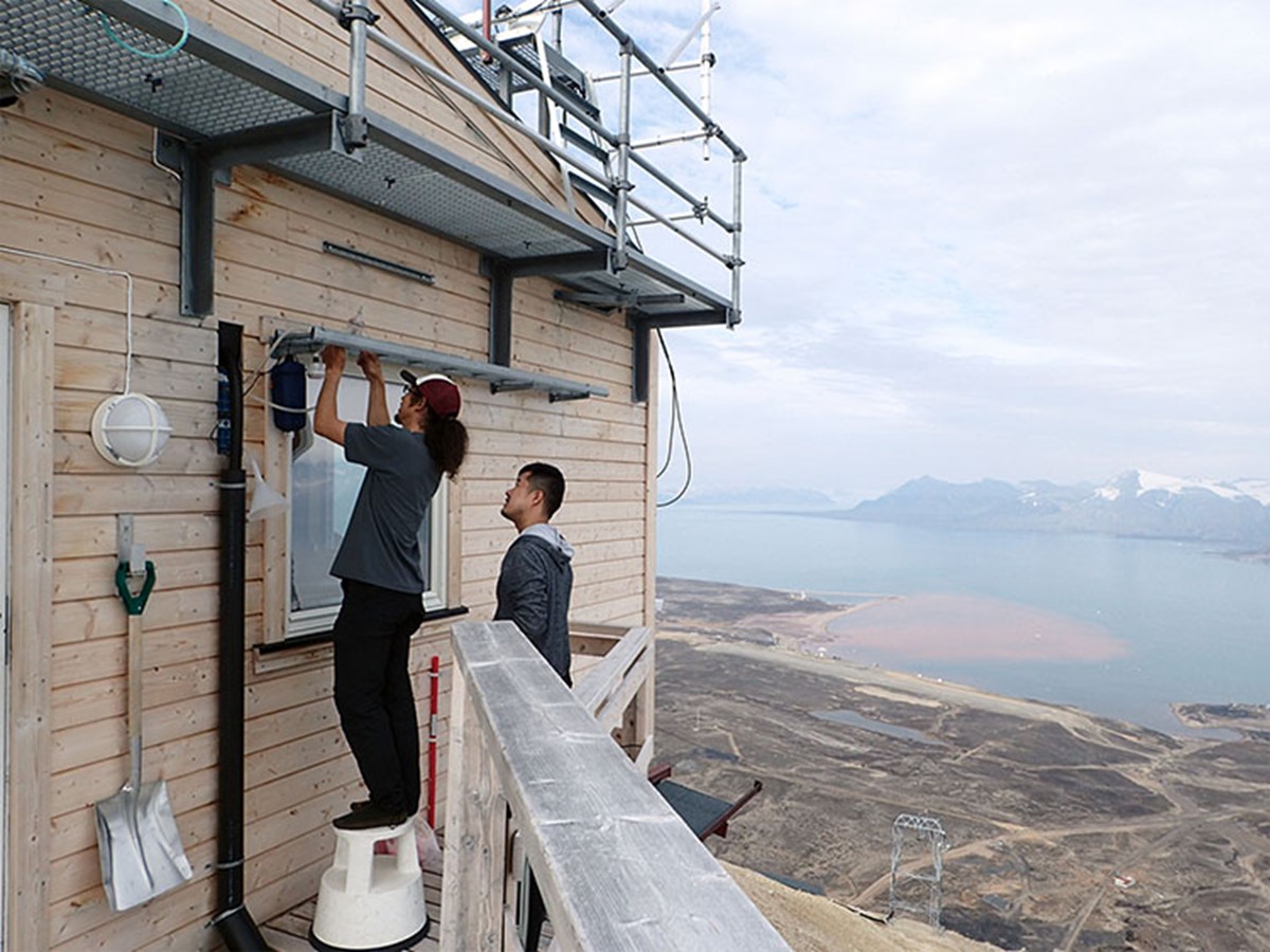 Two former Colorado State University postgraduate students, Jun Uetake on the left and Yutaka Tobo on the right, take the high ground near Ny-Åselund, Svalbard. They set up instrumentation for collecting airborne dust from high latitude and distant sources for ice nucleation investigations during the 2019―2020 Cold-Air Outbreaks in the Marine Boundary Layer Experiment (COMBLE), an ARM field campaign. Both are now teaching at universities in Japan.