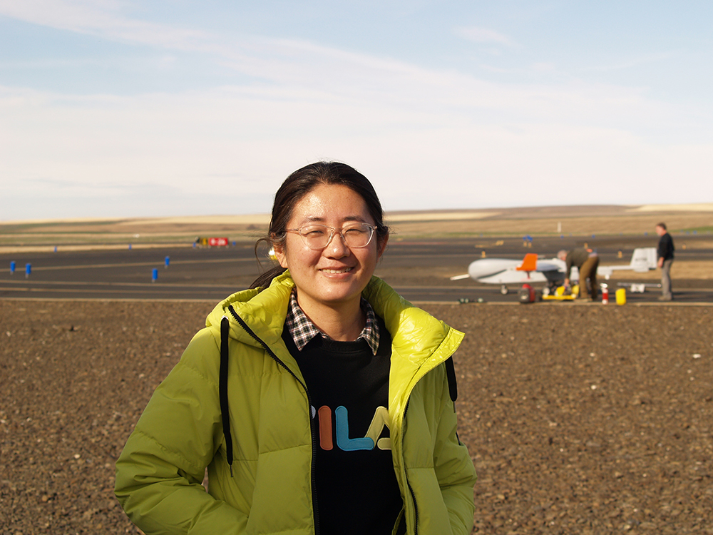 ARM Aerial Facility Science Lead Fan Mei poses with ARM’s ArcticShark uncrewed aerial system in the background at the Pendleton UAS Range in Oregon.