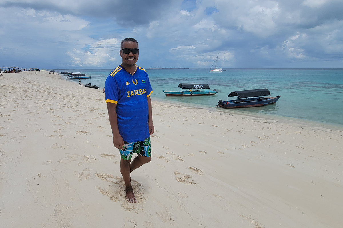 Earth scientist Samson Hagos, on an East African vacation in October 2023, paused on a beach during a snorkeling trip in Zanzibar, a Tanzanian archipelago. Behind him are the kind of shallow convective clouds he has spent so much time studying. Photo is courtesy of Hagos. 