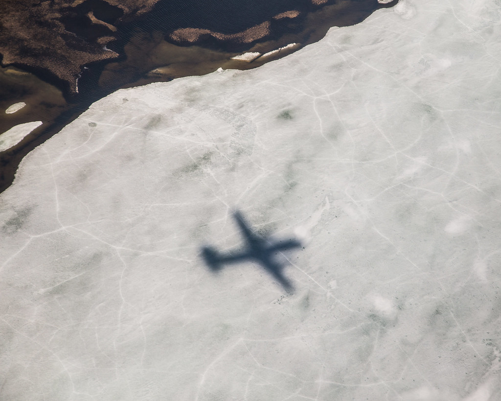 In 2015, an ARM research aircraft casts a shadow over the North Slope of Alaska, where snow has started to seasonally give way to tundra. The exposed green repository of permafrost is at risk of fire because of a predicted large increase in lightning strikes in the Arctic. 