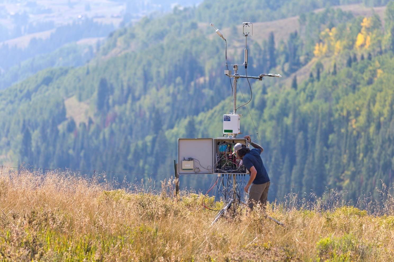In September 2022, during the Surface Atmosphere Integrated Field Laboratory (SAIL) campaign near Crested Butte, Colorado, technician Wessley King checks a combined instrument setup. An eddy correlation flux measurement system measures heat fluxes, which are then compared with surface energy measures from a surface energy balance system.