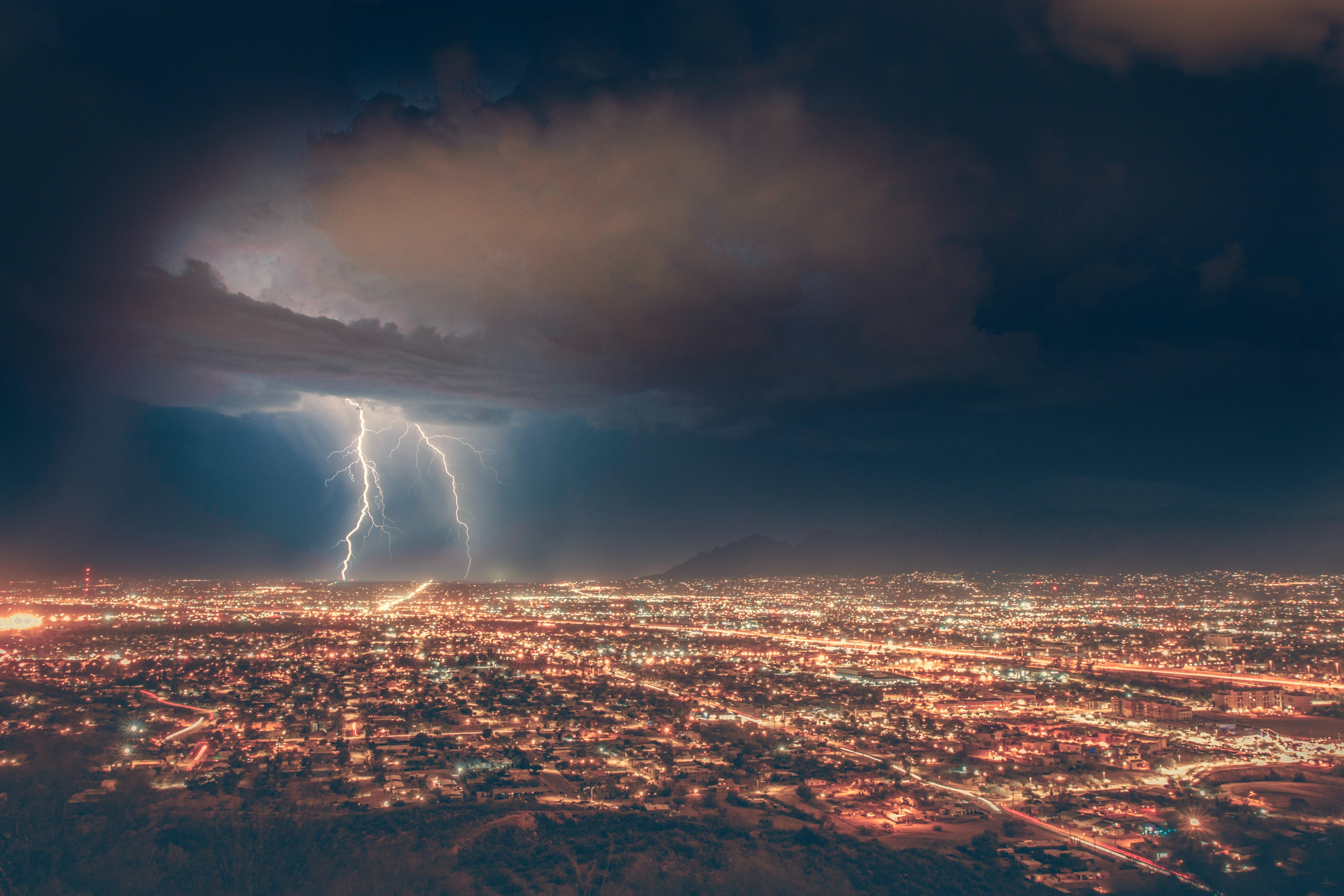 Lightning flashes over a city. TRACER researchers have a database of lightning flash rates by day and hour. Image is courtesy of Unsplash Photos.