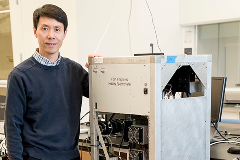 Wang poses with a fast integrated mobility spectrometer used to characterize aerosols from a fast-moving research plane. He developed a prototype while at Brookhaven National Laboratory, which led to one of his patents. Photo is courtesy of Washington University in St. Louis. 